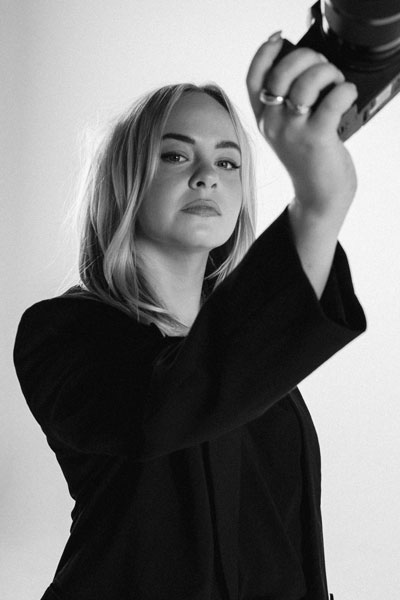 A photo of Kate Karanges in editorial style with her camera. She is the founder and director of The Latest and also oversees the creative and production ecosystems.