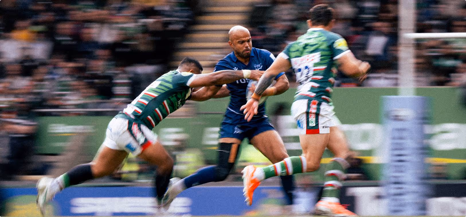 A rugby player in motion, running with the ball, focused on advancing towards the goal.