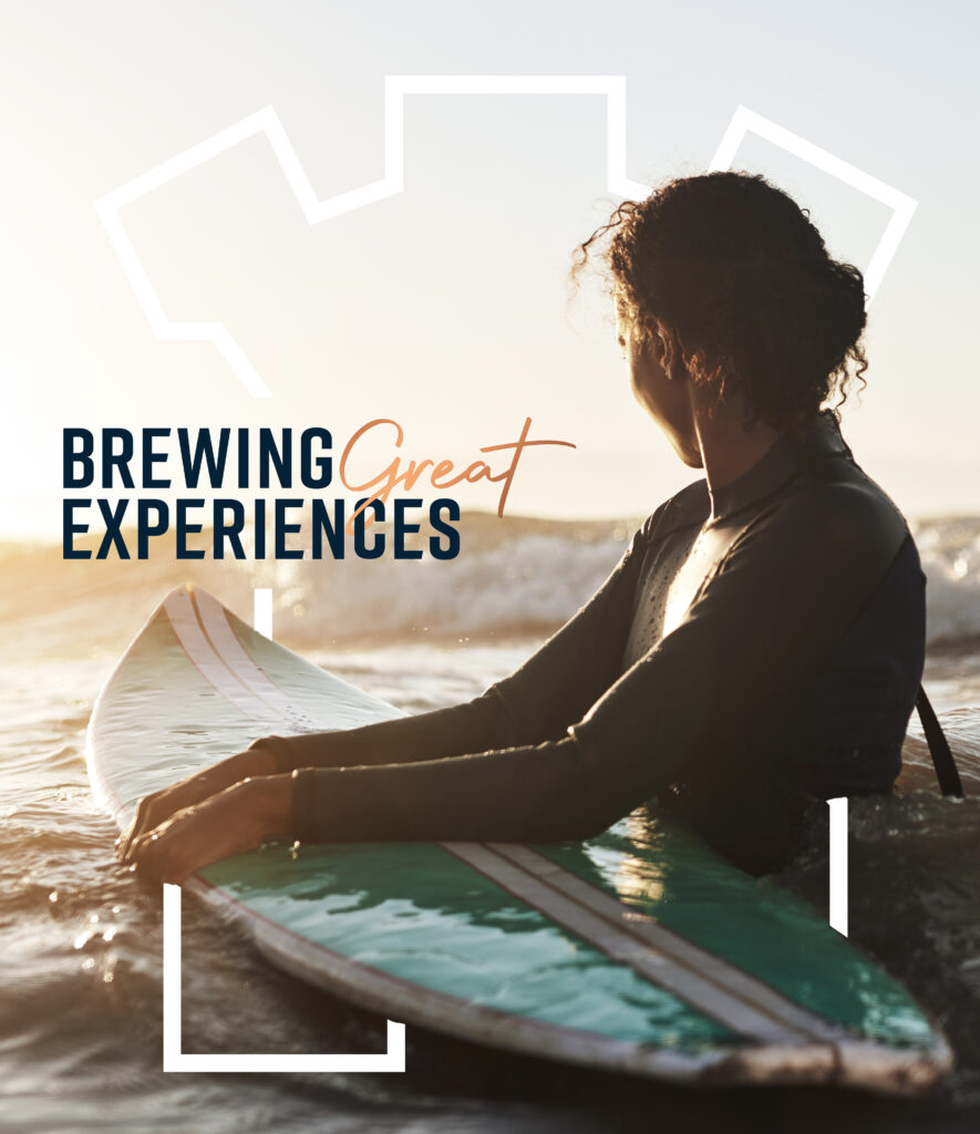 A woman sitting on a surfboard with the phrase "brewing great experiences" displayed above her.
