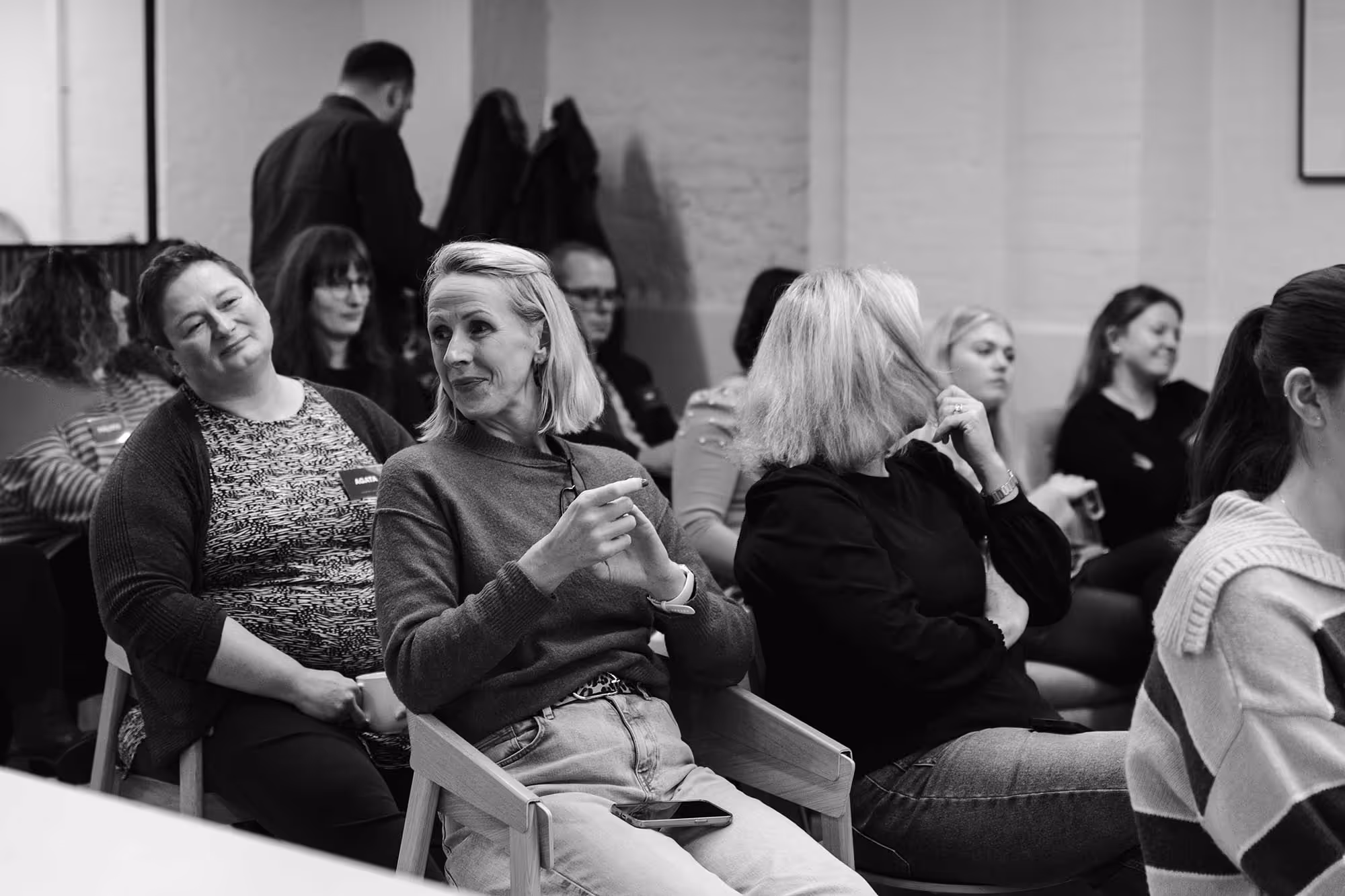 A group of people seated in chairs engaged in conversation, sharing ideas and laughter in a casual setting