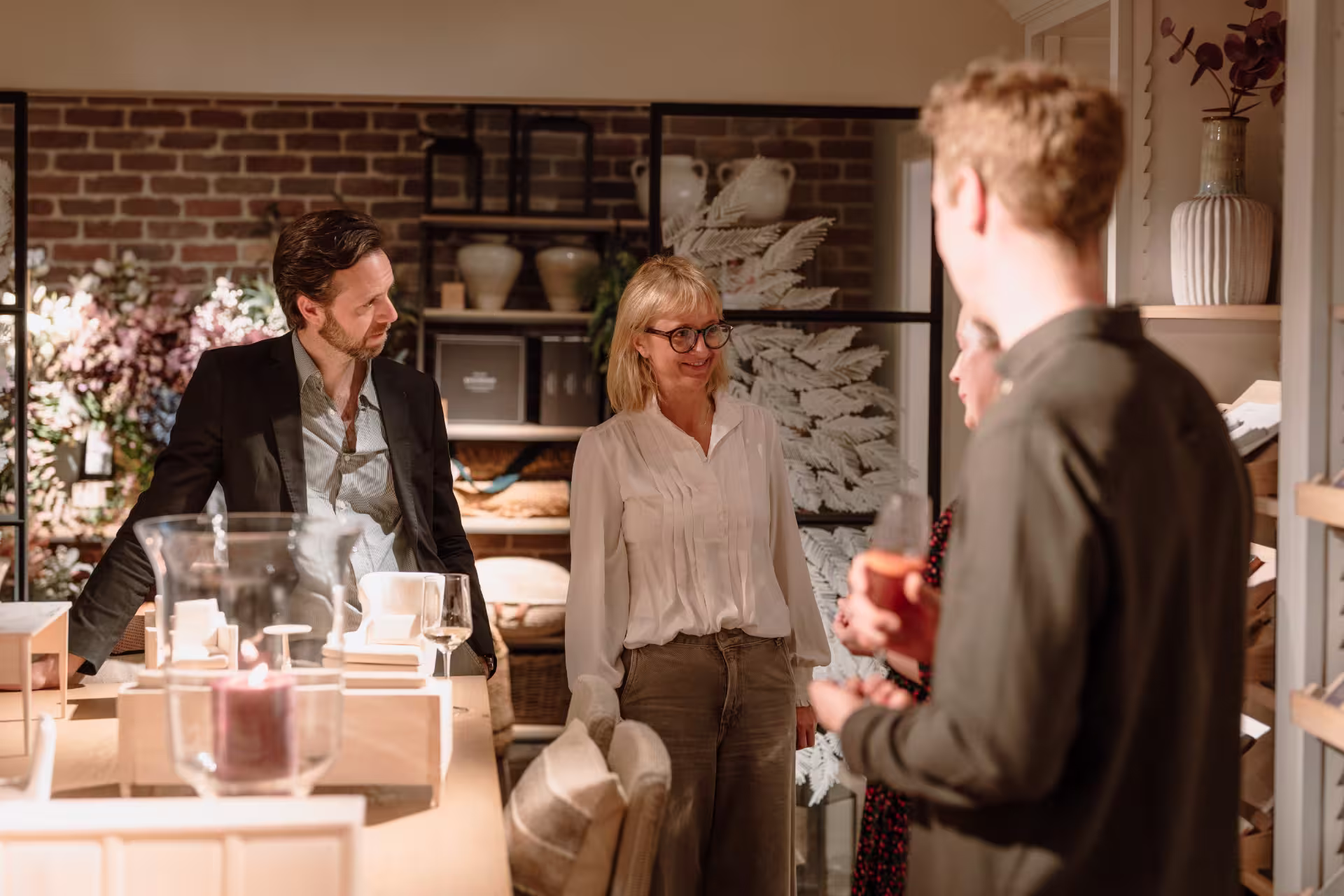 Three people browsing items in a store, engaged in conversation while examining various products on display.
