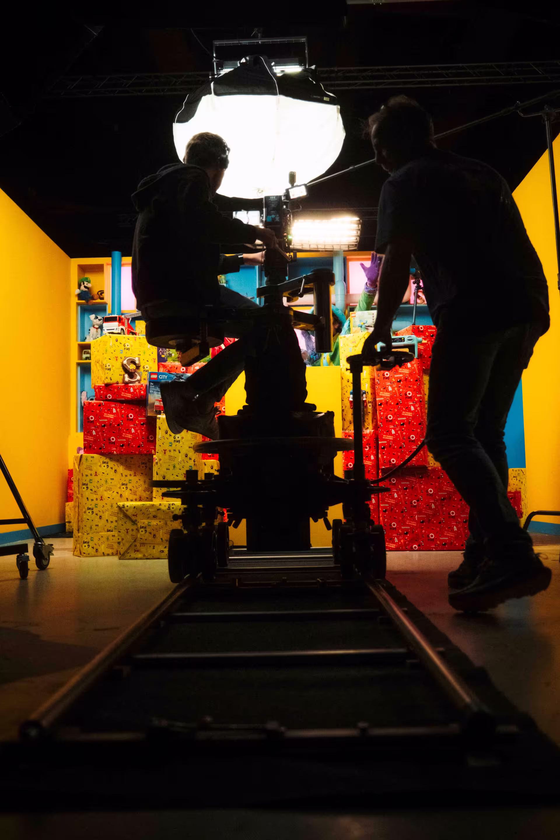 Two individuals collaborate on a set featuring a bright yellow background.