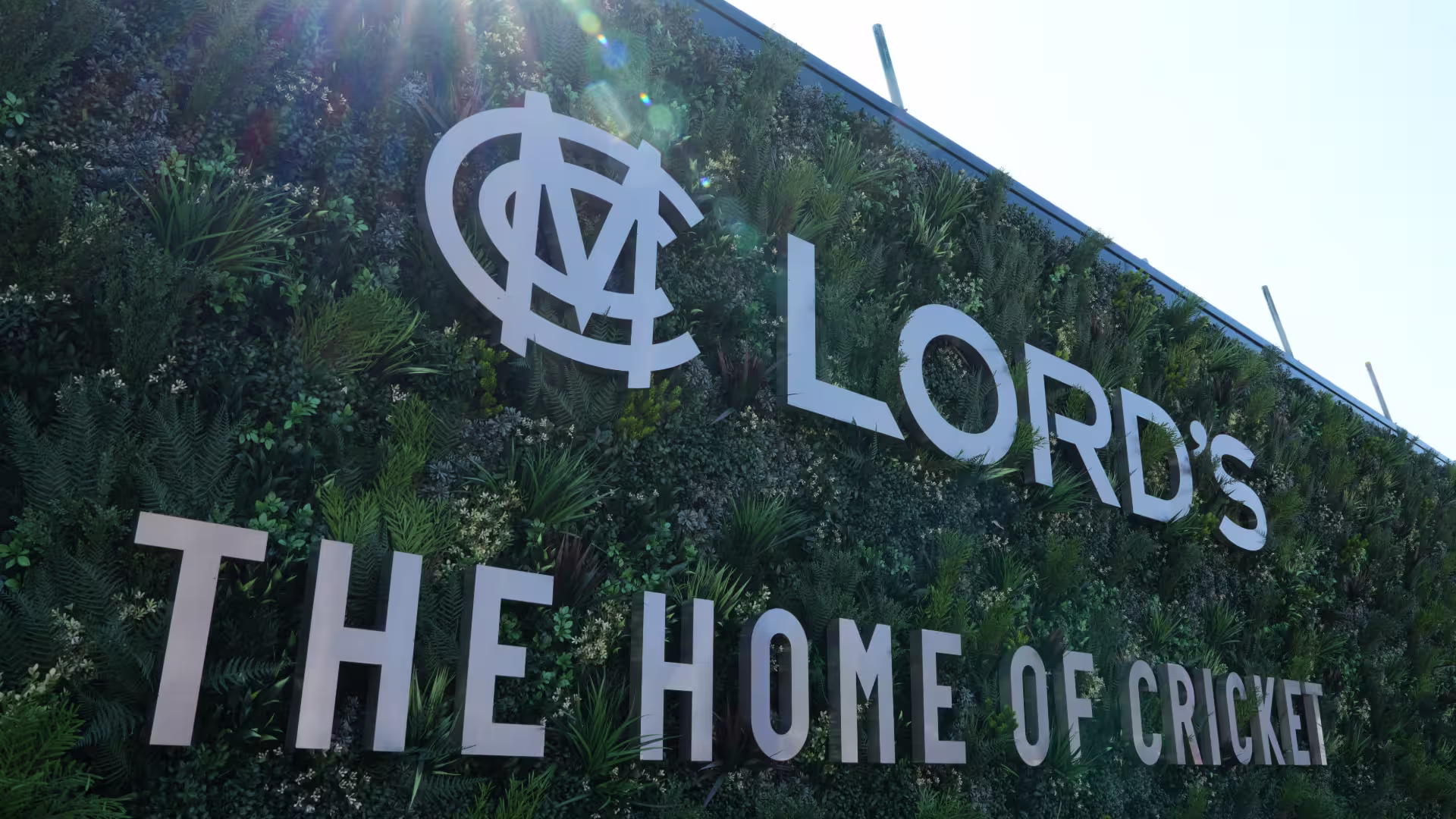 Lord's Cricket Ground living wall sign reading 'Lord's – The Home of Cricket' with the MCC monogram, set against a lush green plant wall with sun flare