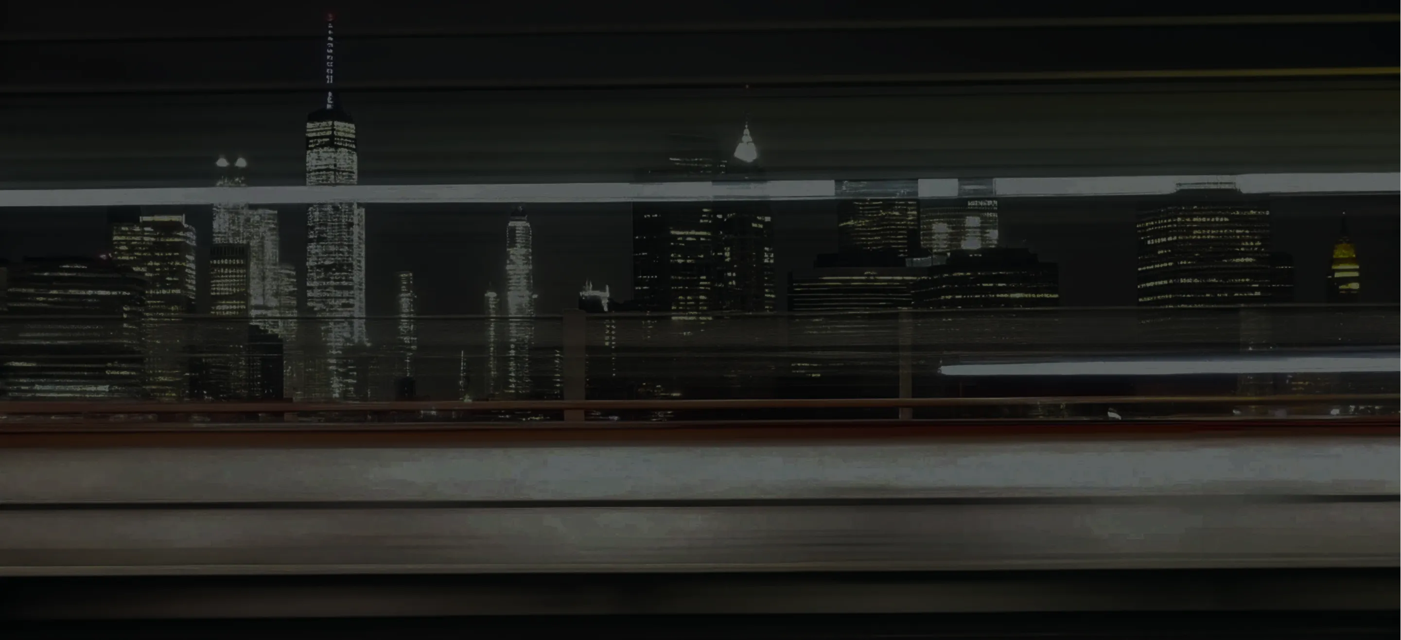 Blurred light trails of vehicles in front of illuminated city skyline at night.