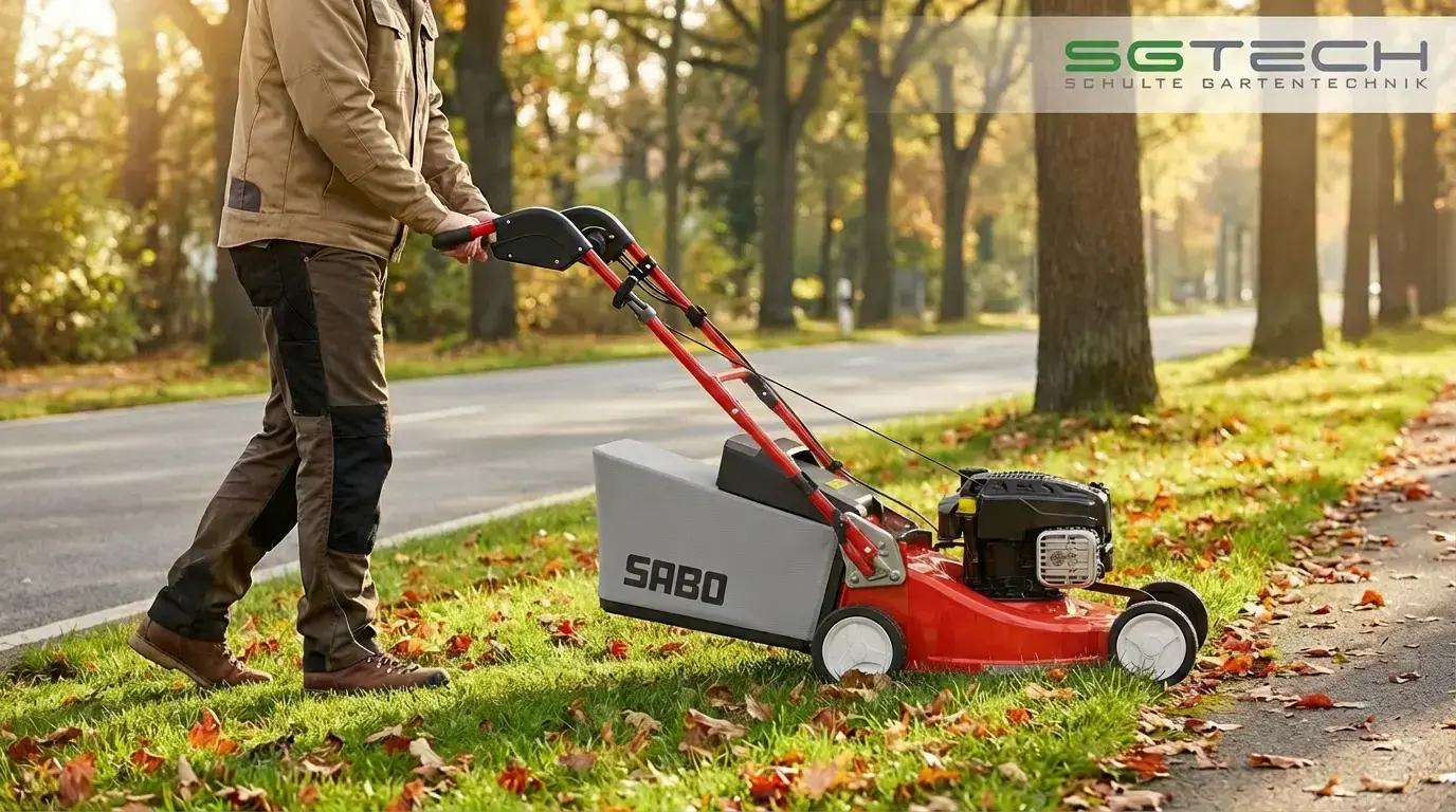 Arbeiter mäht mit Sabo 43-PRO Rasenmäher einen Grünstreifen neben der Straße im Herbst, sonniges Wetter, Blätter fallen.