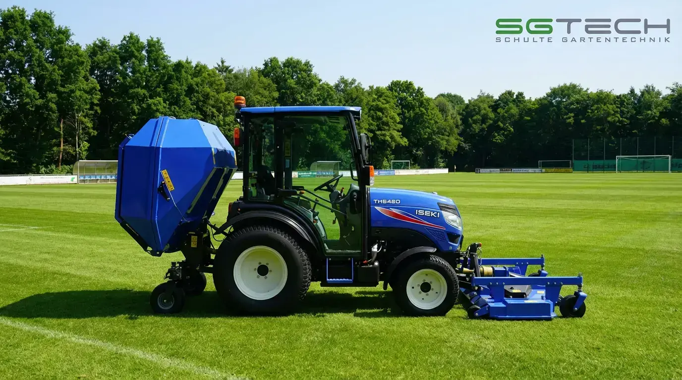 Iseki TH5420AHLK Traktor auf Fußballplatz mit Mähwerk & Grasfangcontainer. Ein blauer Kompakttraktor mäht grünes Gras im Sommer.