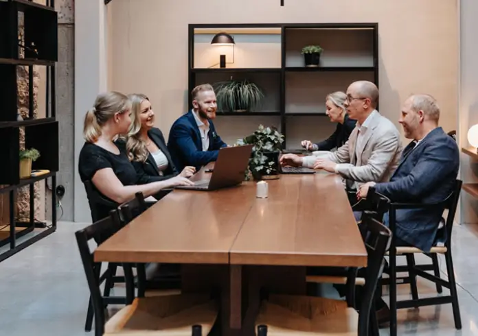 Group of professionals seated around a table having a business meeting in a modern office.
