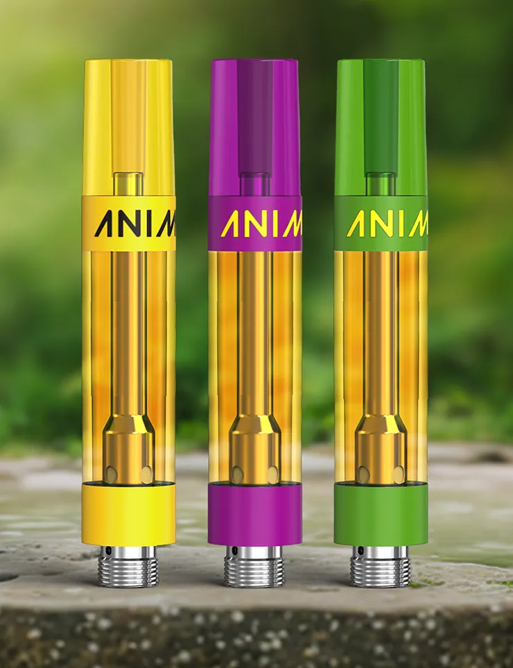 Three ANIMAL branded vape cartridges in yellow, magenta and green on a stone surface.