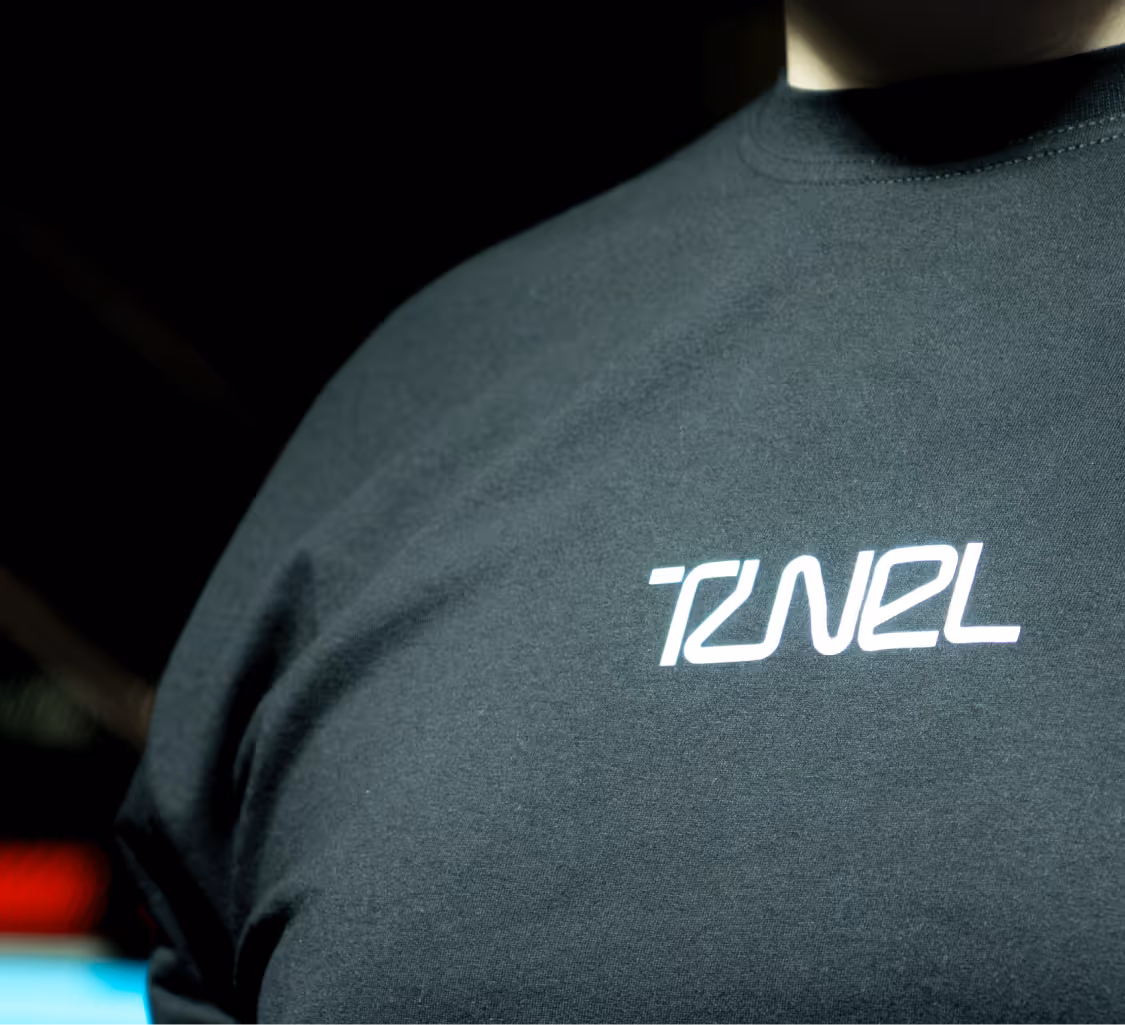 Close-up of a black T-shirt with the white text 'TUNEL' on the chest.