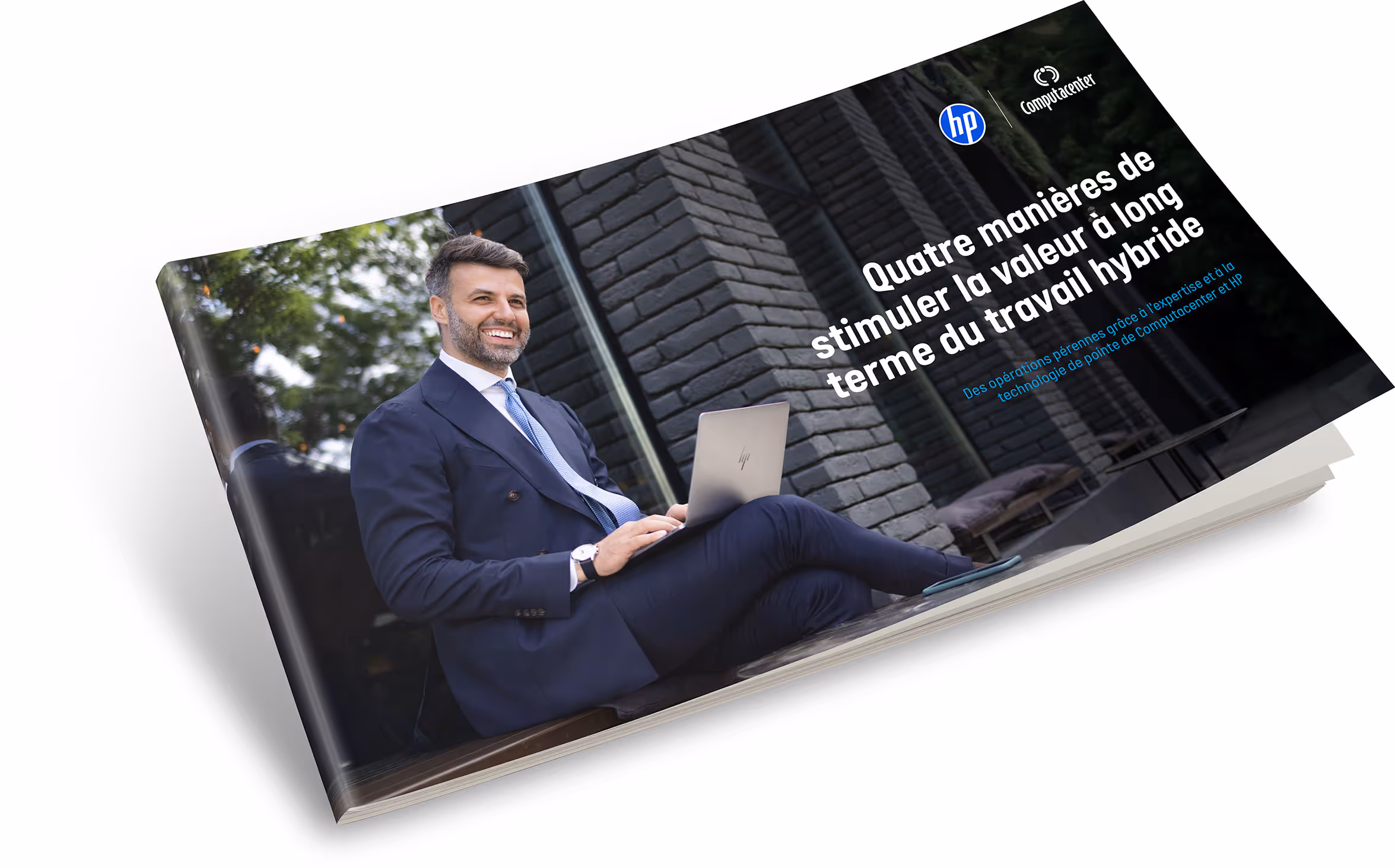 Homme en costume assis dehors avec un ordinateur portable HP sur les genoux, souriant devant un mur en briques noires.