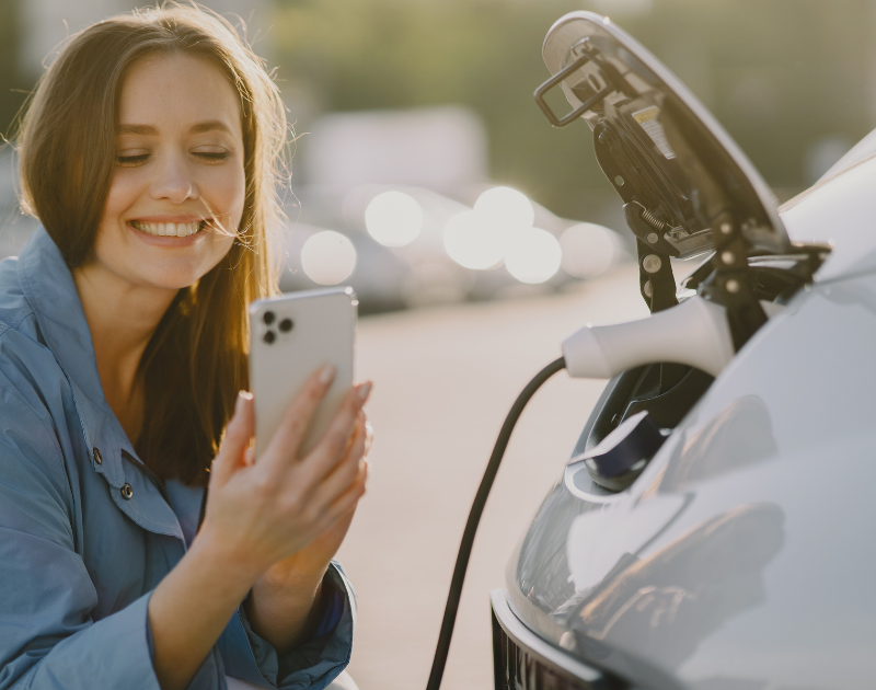 Femme charge voiture électrique avec son téléphone