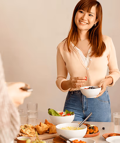 A woman smiling at a colleague, eating lunch