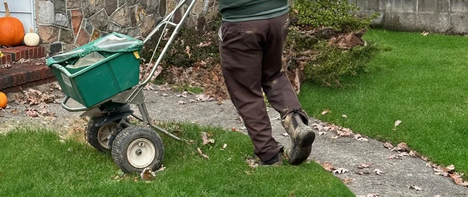 Man spreading granular fertilizer on grass in Wayne, NJ.