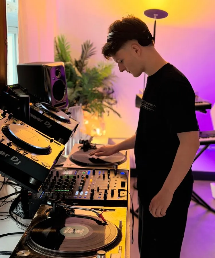 A man is DJing in a stunning DJ studio at London Sound Academy using CDJs and turntables