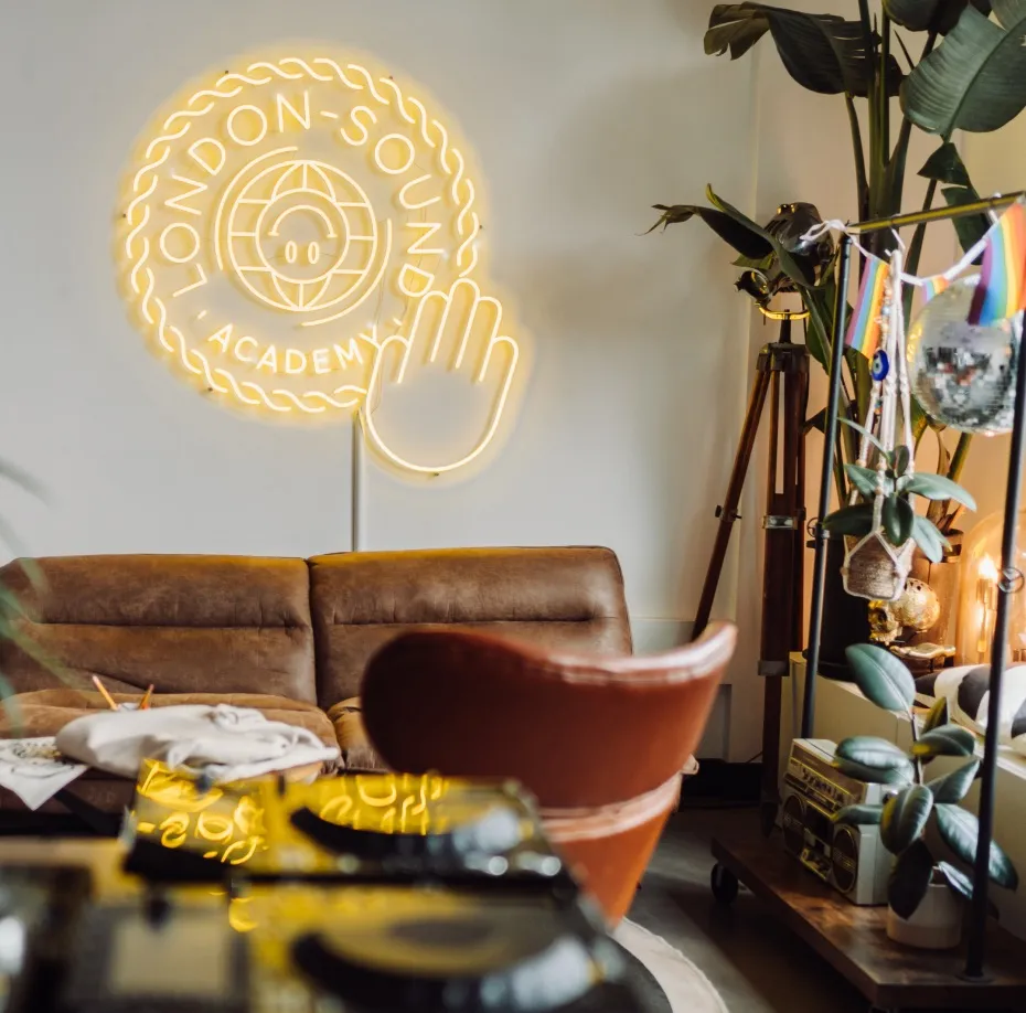 A neon sign that reads 'London Sound Academy' hangs in a luxurious studio