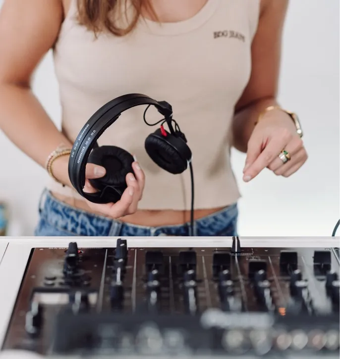 A woman holds a pair of DJ headphones ready for the next mix
