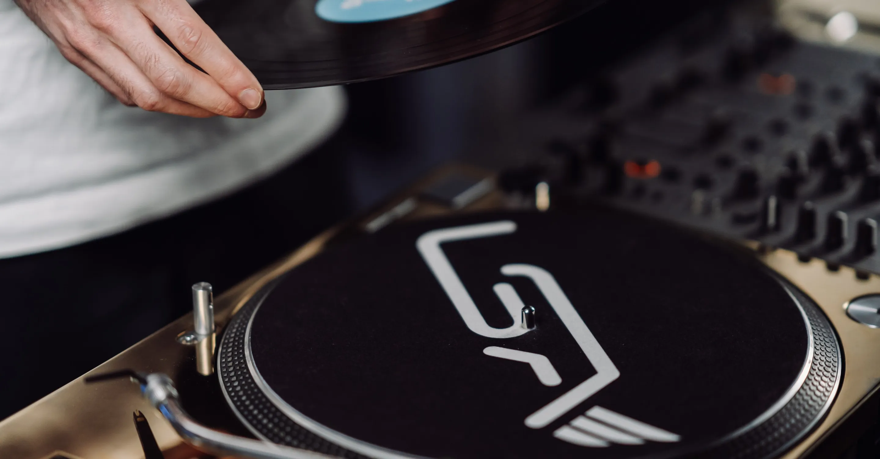 Close-up of a hand placing a vinyl record on a DJ turntable.