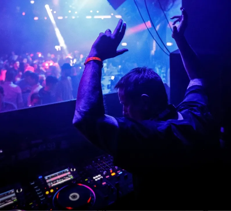 A DJ holds his hands in the air during his DJ gig at Ministry of Sound