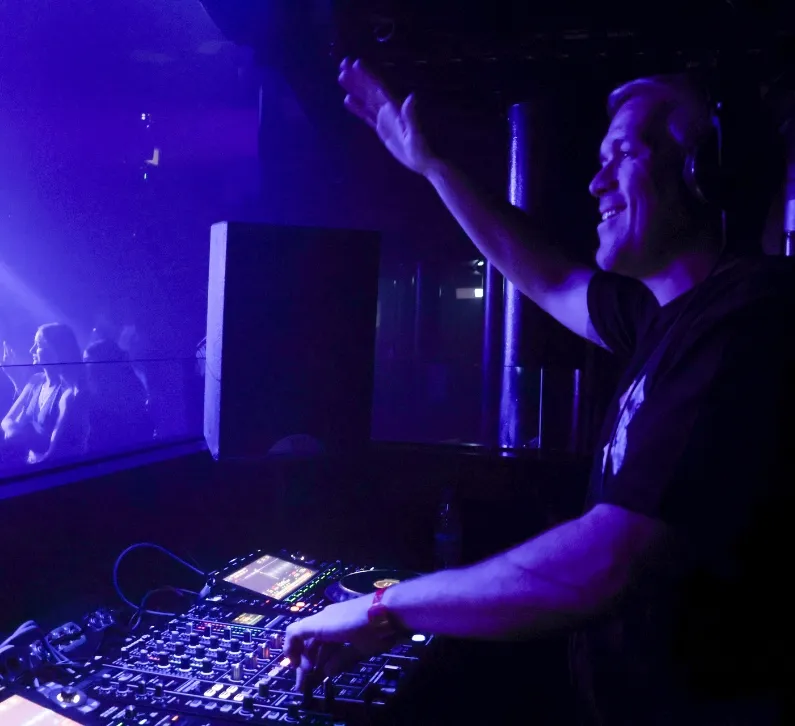 A smiling DJ is waving his hand toward the audience at an LSA DJ gig at Ministry of Sound