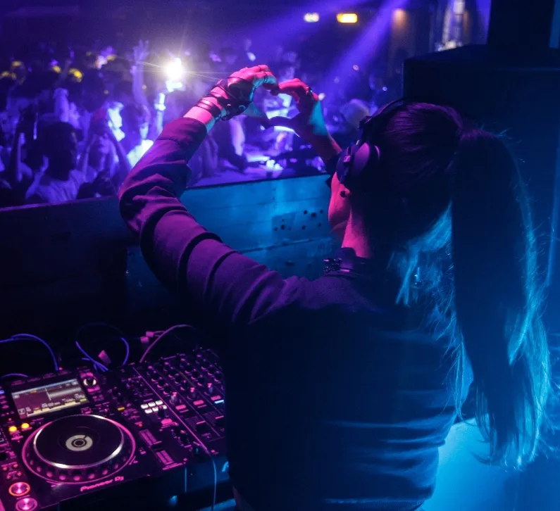 A DJ holds her hands in the air in a heart shape signalling to the crowd during a DJ performance in London