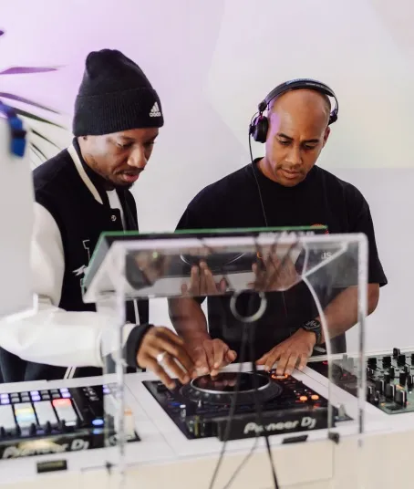 A professional DJ instructor teaches a beginner DJ course student the ropes.
