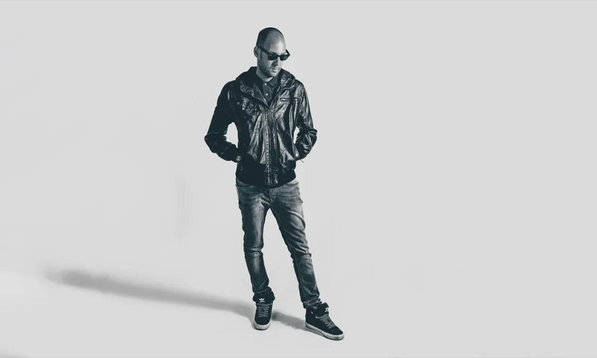 A full-body DJ portrait of a male DJ in the studio