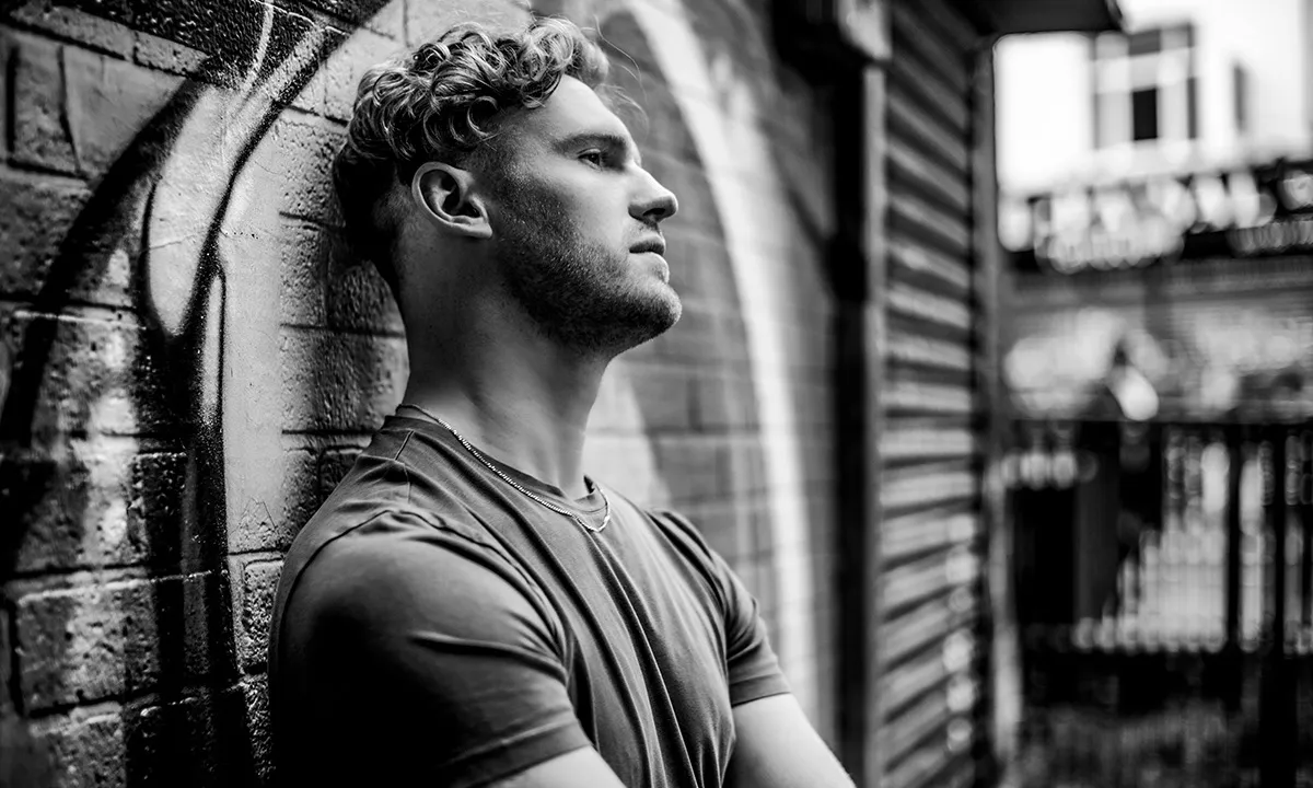 A classic black and white photo of a DJ leaning against a wall