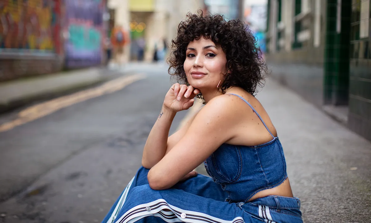 A female DJ wearing a blue tracksuit poses for the camera during her DJ photoshoot