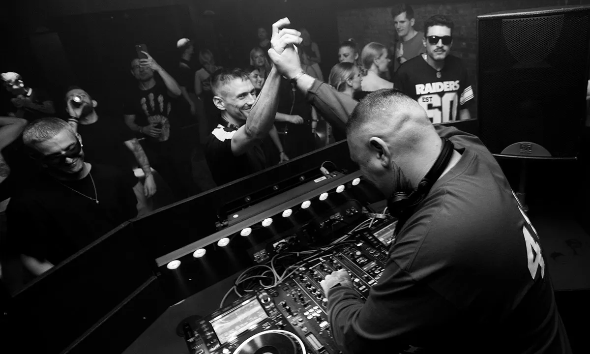 A male DJ shakes hands with an audience member in a candid live DJ photo