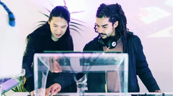 A woman is learning how to DJ behind a professional DJ booth at London Sound Academy