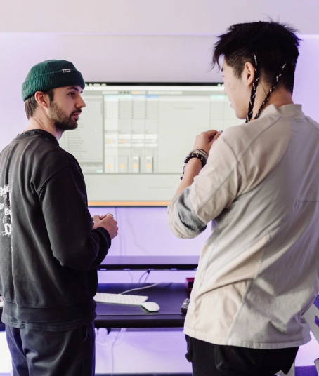 A music production tutor explains how to create beats while a student listens
