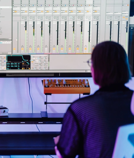A music producer is working at a large production station with Ableton