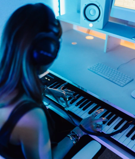 A female production student is playing the keyboard programming a melody