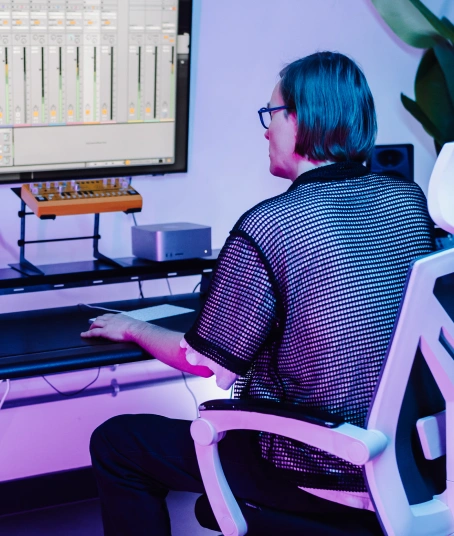 A music producer is sitting in a recording studio at London Sound Academy in front of an impressive array of equipment