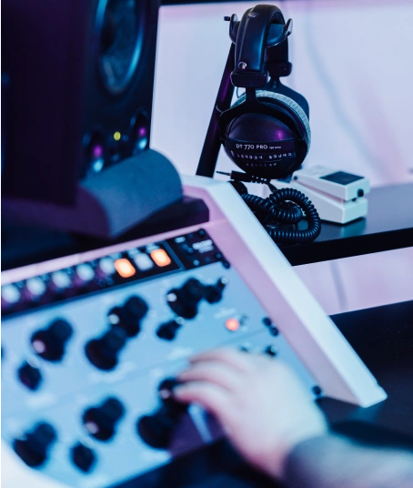 A hand is turning knobs on a music production compressor