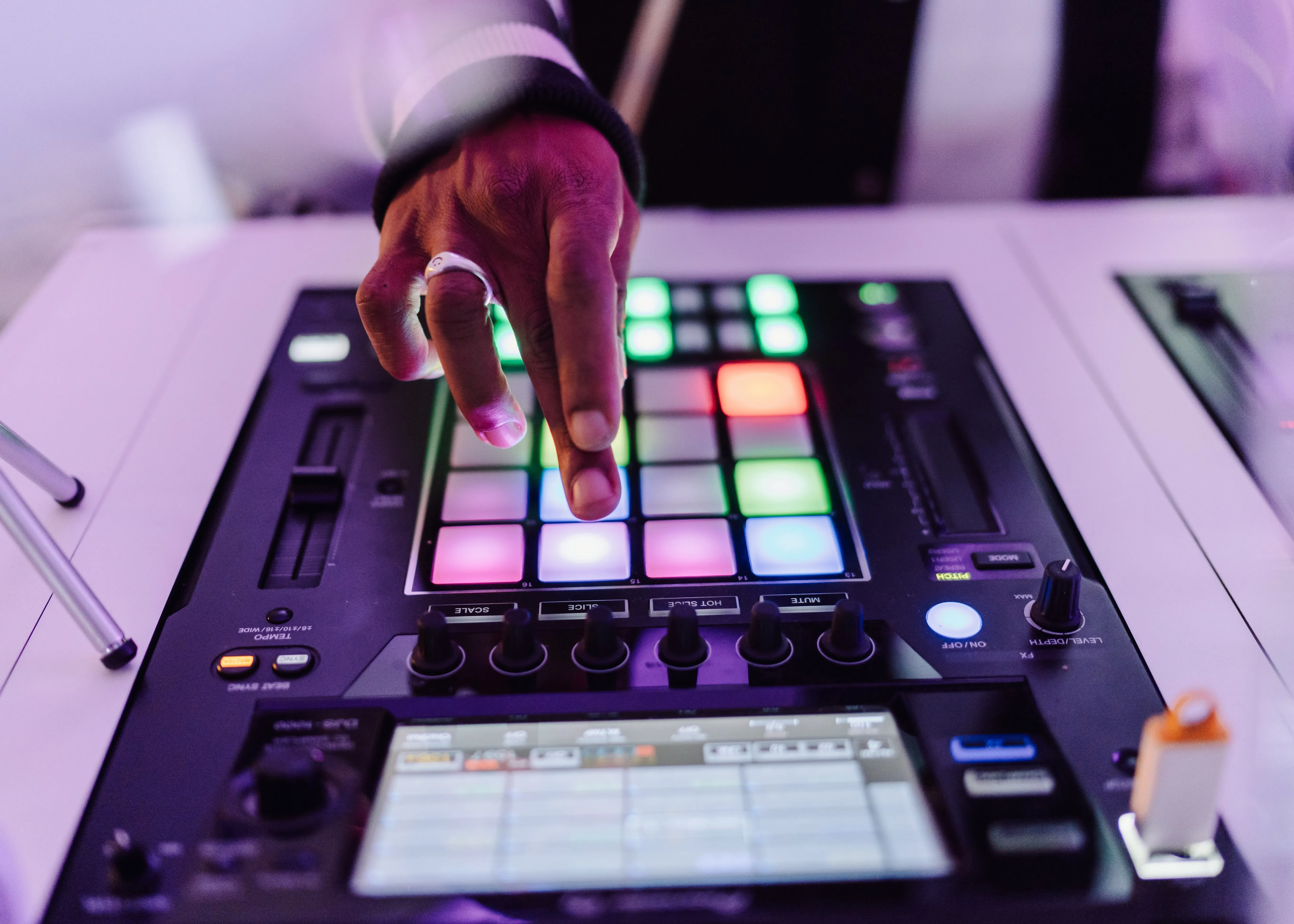 A DJ drums the pads on an advanced DJ sampler during a hybrid DJ set