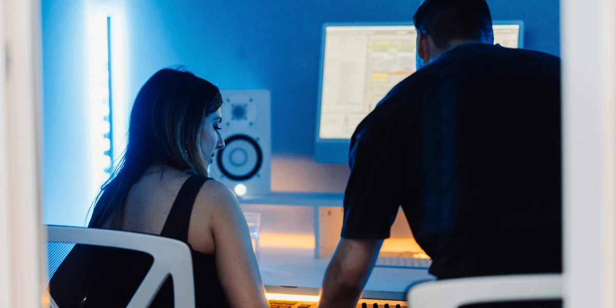 A producer teaches a new music production course student how to make music while sitting in a pro audio recording studio in London