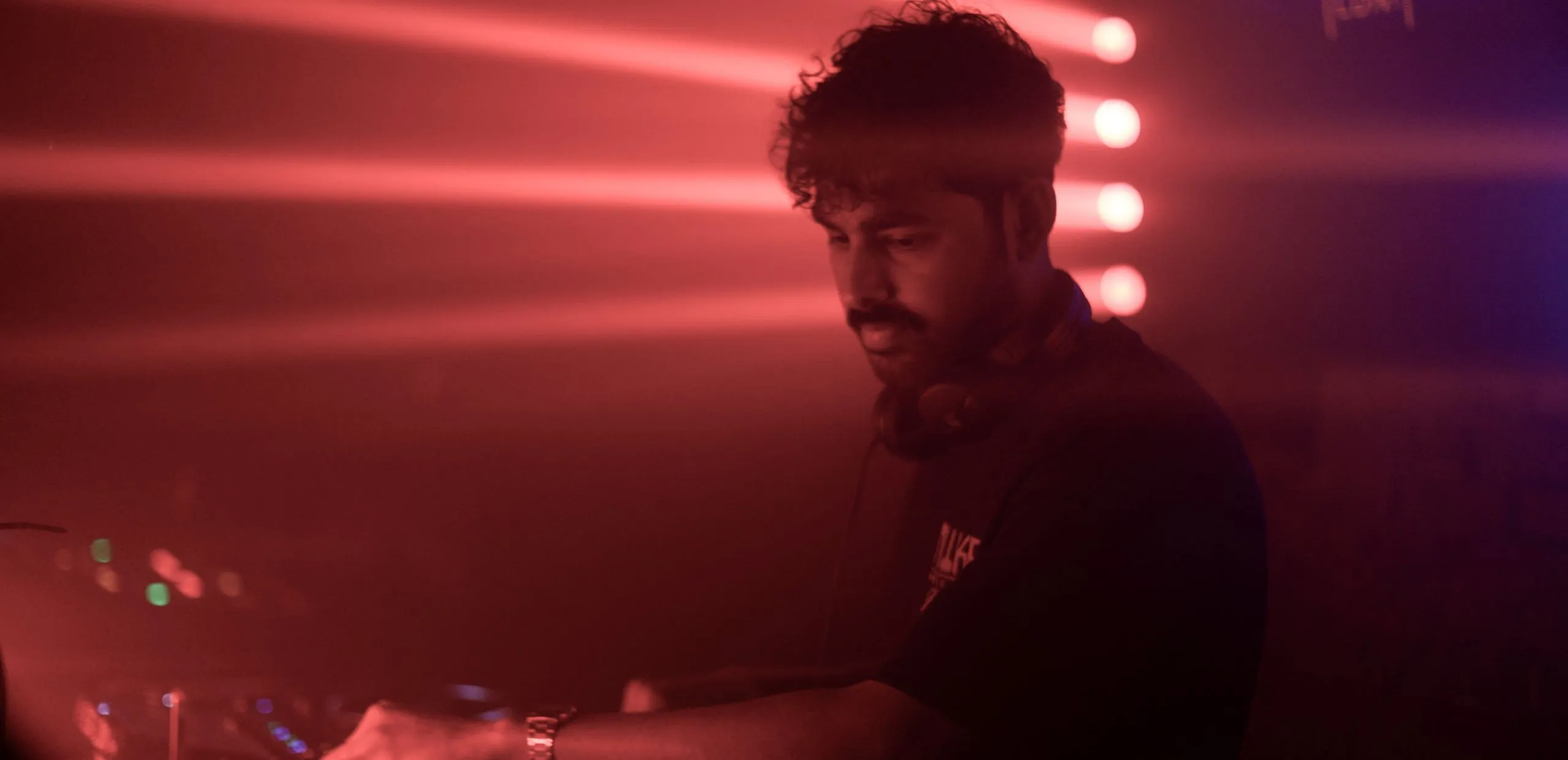 A man DJs at Egg London bathed in red light and lasers
