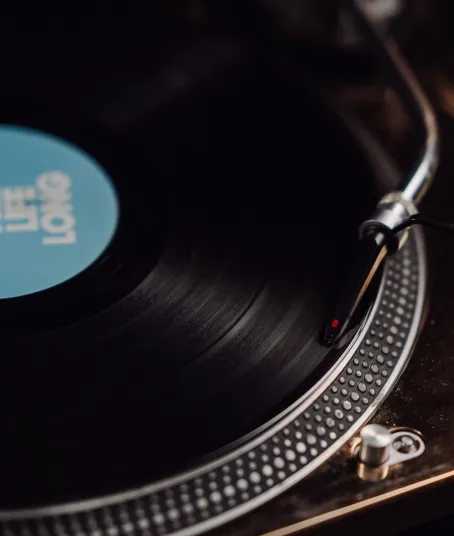 A vinyl record spins on a gold turntable while the needle plays the track