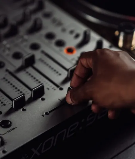 A man is mixing vinyl with a DJ mixer crossfader