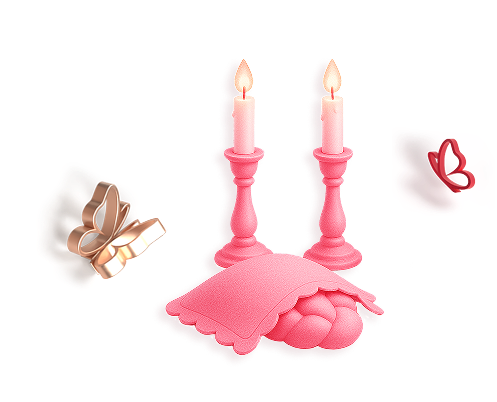 Two pink lit candles on holders next to two challos covered with a cloth and two decorative butterflies one gold and one pink.