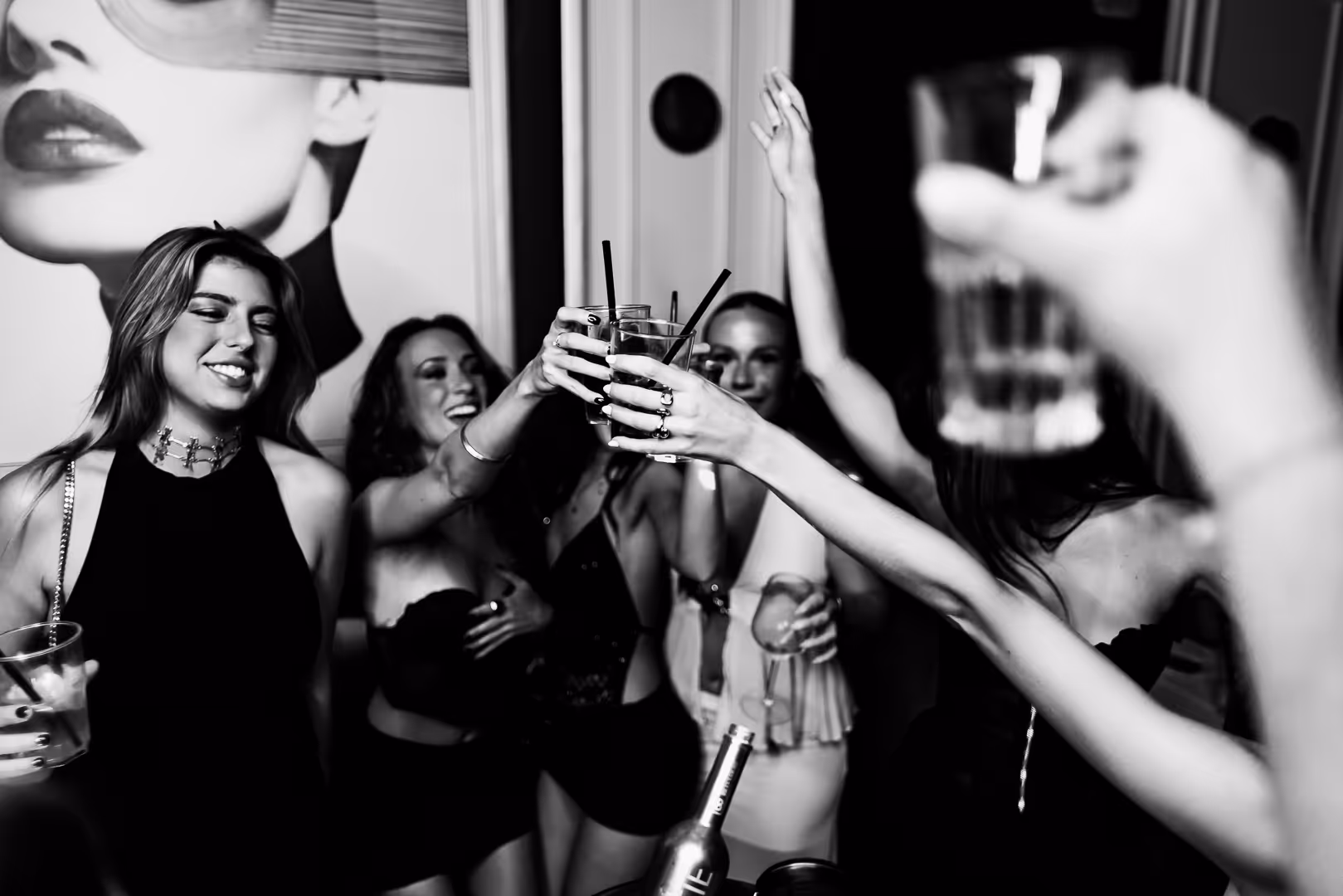 Group of young women raising glasses for a celebratory toast at a party.