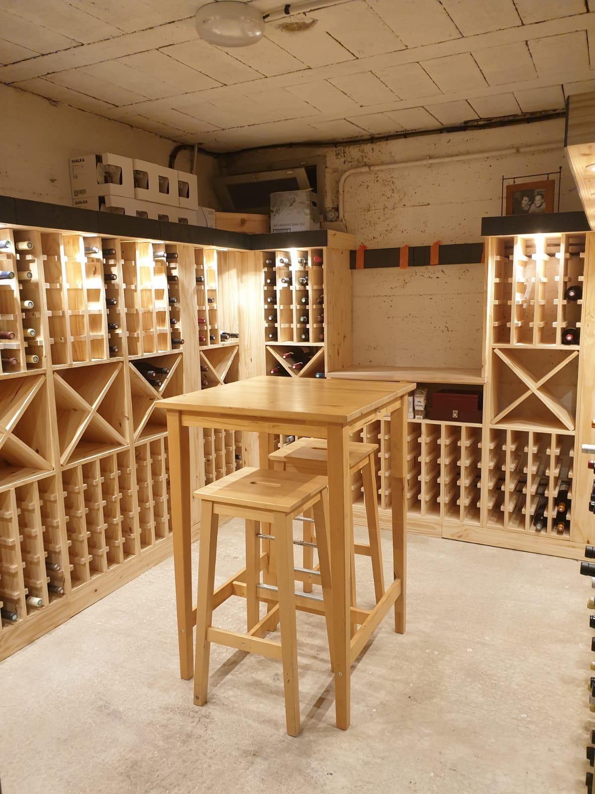Cave à vin en bois avec table haute et tabourets.