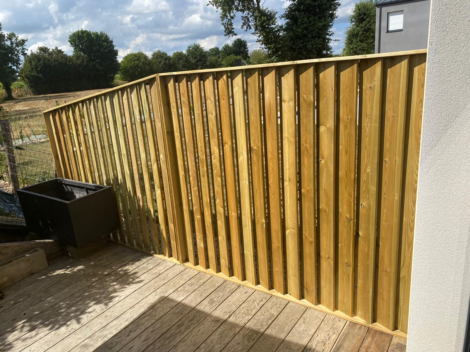 Barrière en bois neuve sur une terrasse extérieure.