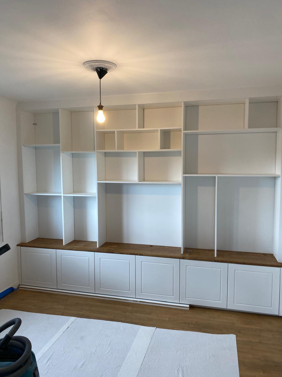 Meuble mural blanc avec étagères et rangements bas en bois.