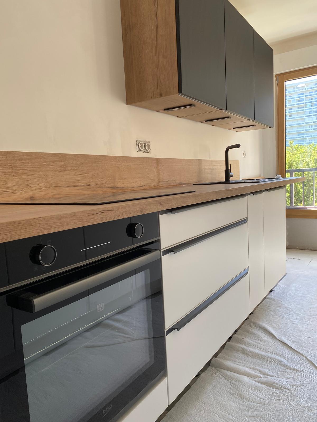 Cuisine moderne avec meubles noirs et blancs et plan de travail en bois.