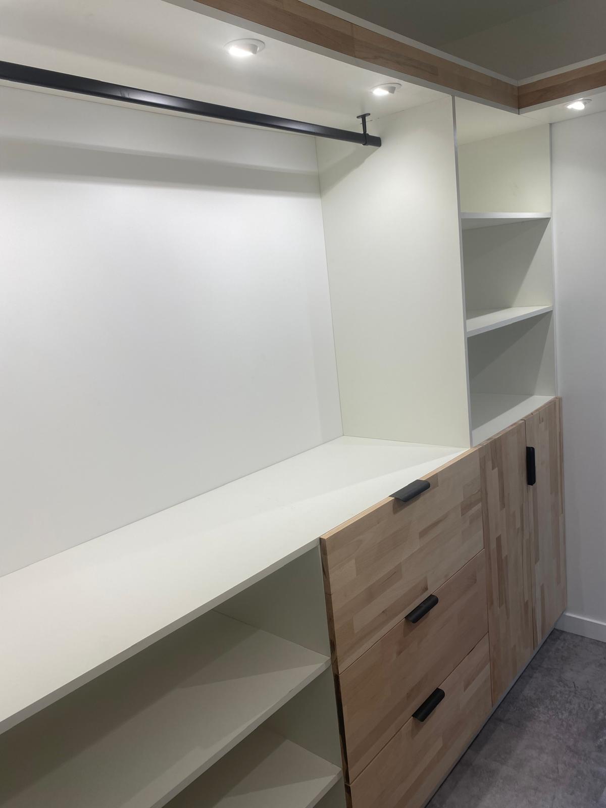Dressing sur mesure avec étagères et tiroirs en bois clair.