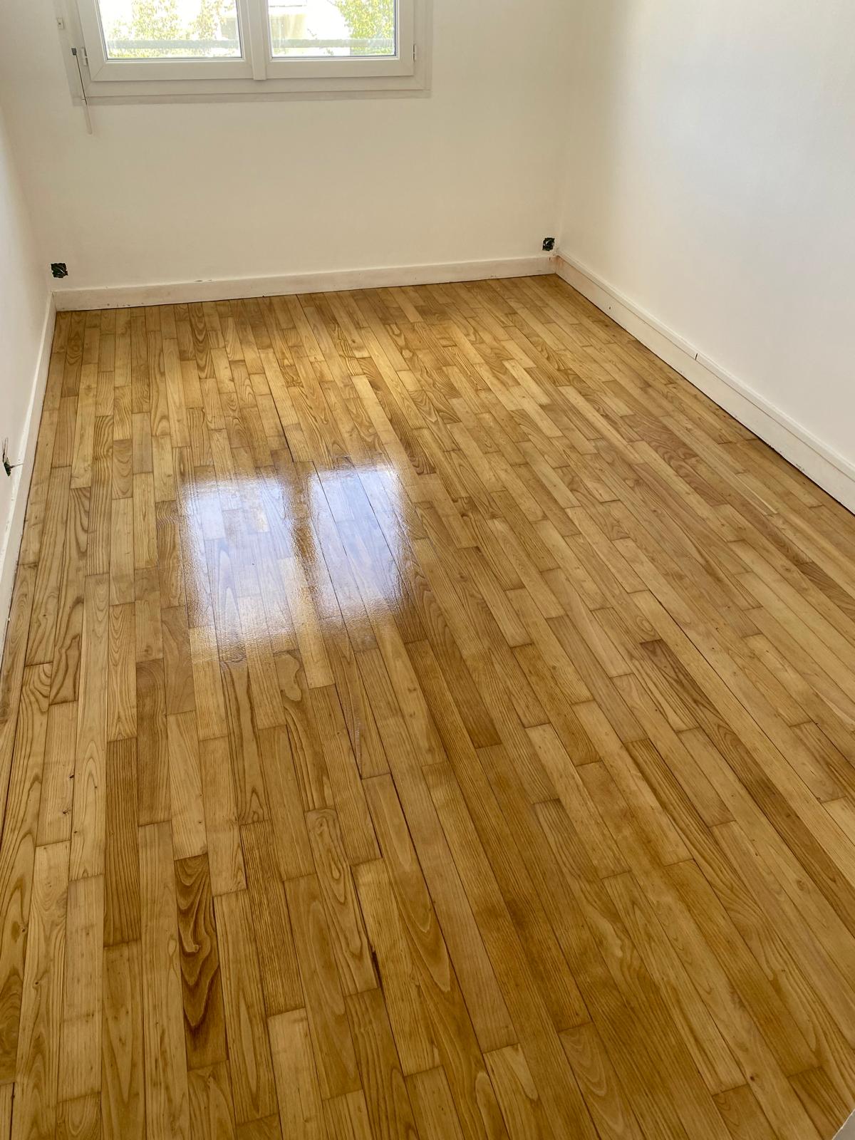 Chambre vide avec parquet bois clair.