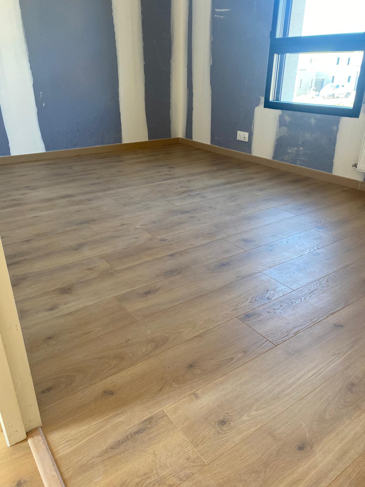 Pièce vide avec parquet bois clair.