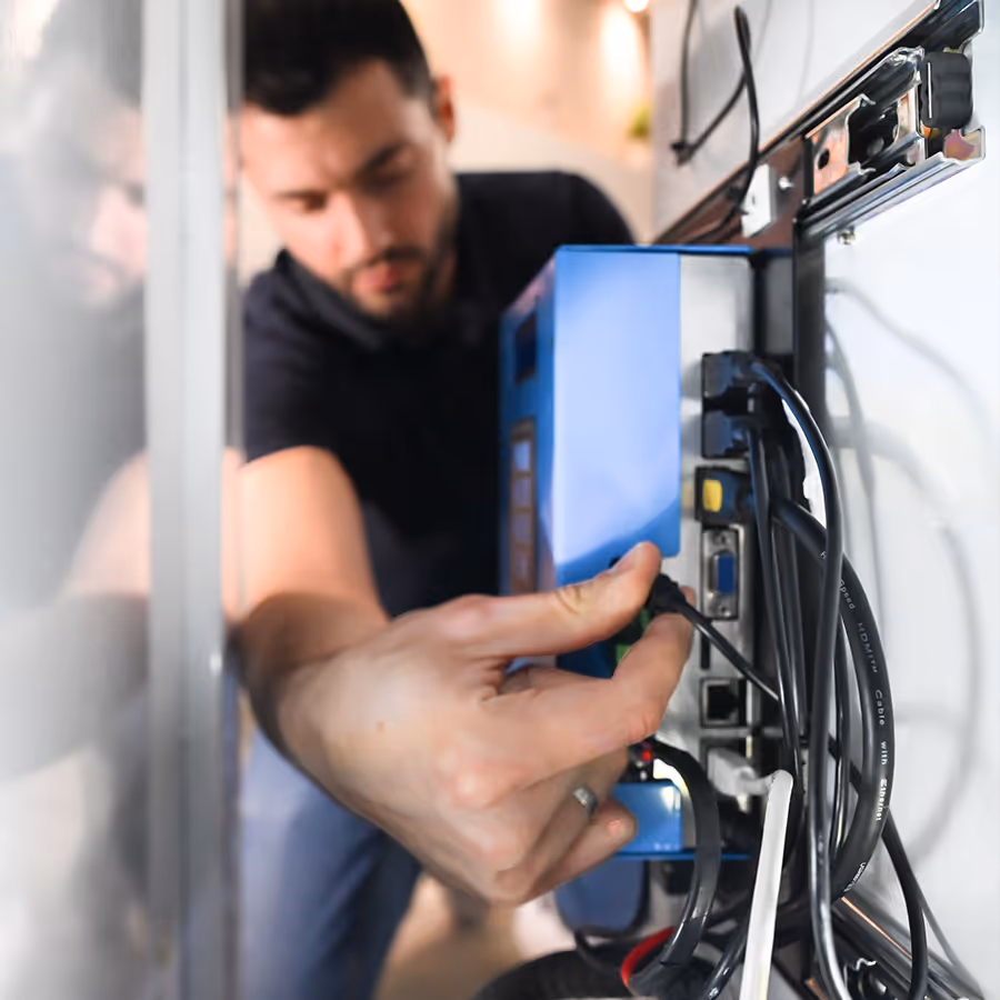 Person connecting cables to the back of a blue electronic device with multiple ports and wires.